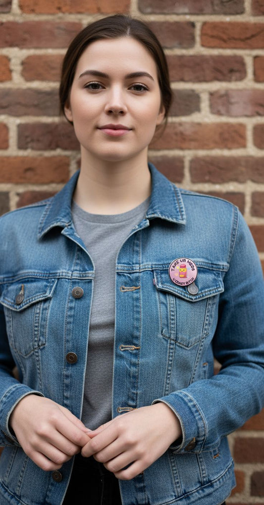 Person wearing a blue denim jacket with a badge against a brick wall